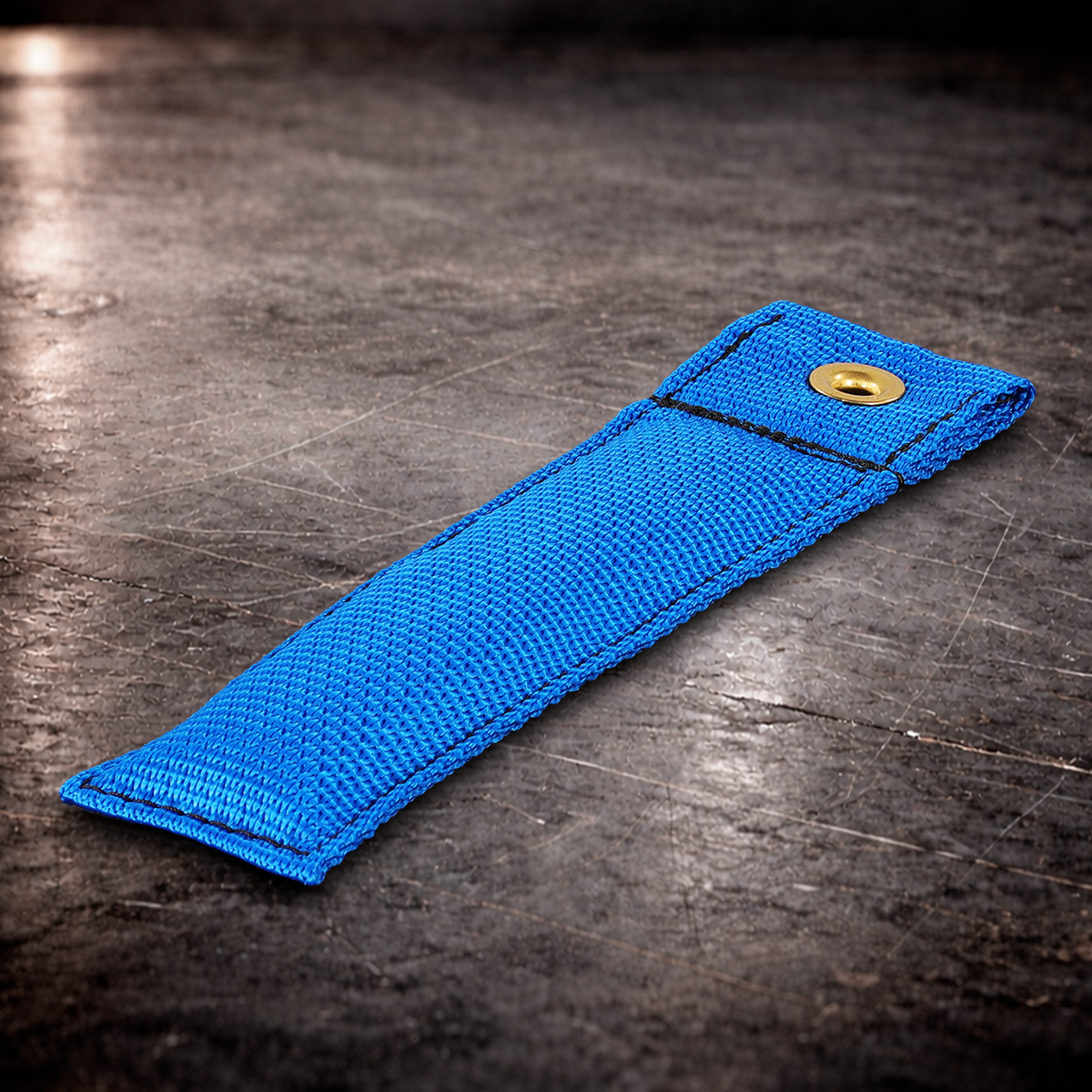 6 inch blue marker with grommet on industrial surface blue fabric marker close up stitching detail 6 inch grip marker with metal grommet blue blue set marker on dark warehouse background film production marker blue with grommet.