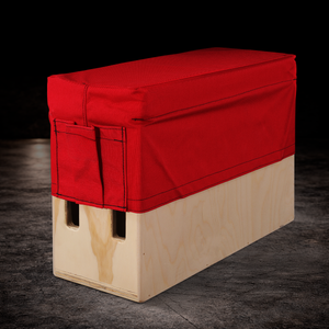Red padded horizontal apple box seat cover with side storage pocket for professional film production and on-set seating
